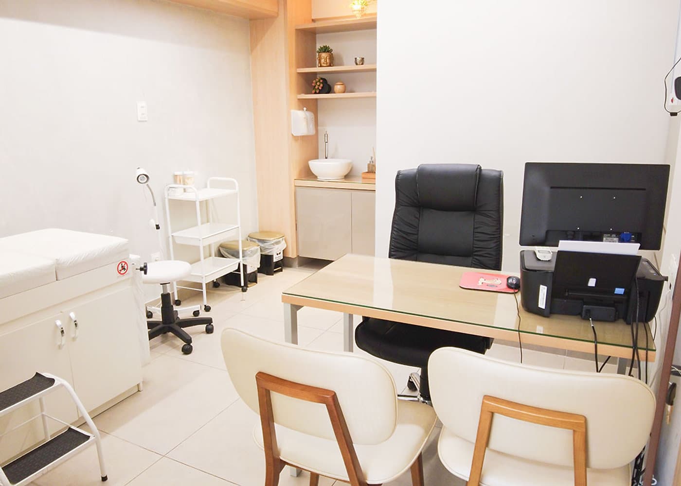 Sala de atendimento da unidade Lourdes do Instituto Hiraki com maca, pia, carrinho auxiliar e mesa com computador